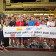 Viele Läuferinnen und Läufer halten beim Klagenfurt Airport Night Run 2025 ein Transparent hoch.