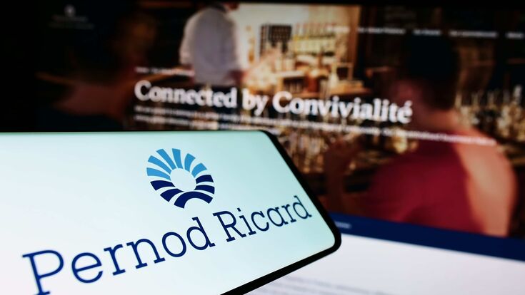 Pernod Ricard-Schriftzug auf einem Smartphone, im Hintergrund verschwommen eine Bar.