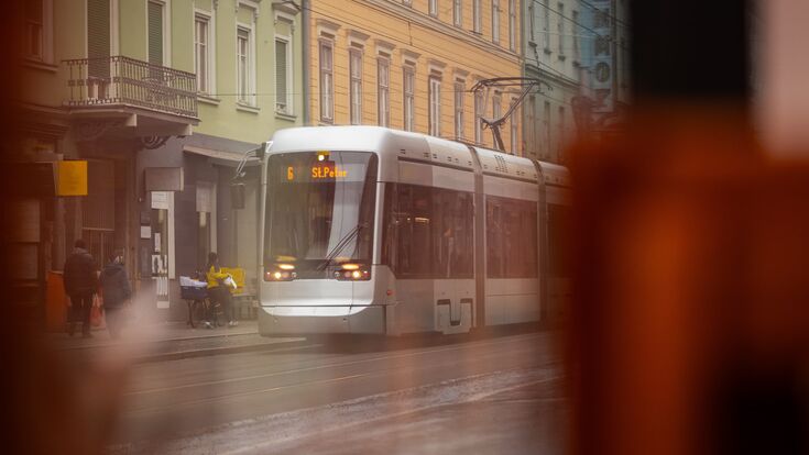 Verschwommene Ansicht auf eine Straßenbahn, die durch die grazer innenstadt fährt.