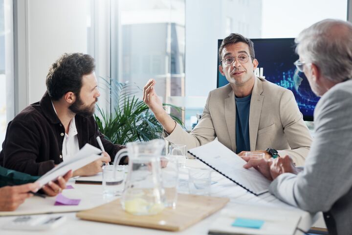 Vier Führungskräfte oder Manager in einem Meeting an einem Tisch.