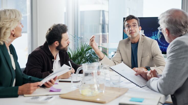 Vier Führungskräfte oder Manager in einem Meeting an einem Tisch.