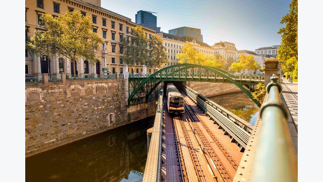 U-Bahn in Wien fährt über Zollamtssteg-Brücke und Wasserkanal darunter.