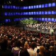 Publikum blickt bei Eröffnung der Salzburger Festspiele auf das schwarz gekleidete, spielende Orchester auf der Bühne