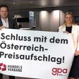 Rainer Will vom Handelsverband & Barbara Teiber von der GPA halten ein Transparent, das Ende von Österreich-Preisaufschlag fordert.