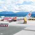 Eine Malta Air-Maschine steht am Flughafen Klagenfurt, Berge im Hintergrund.