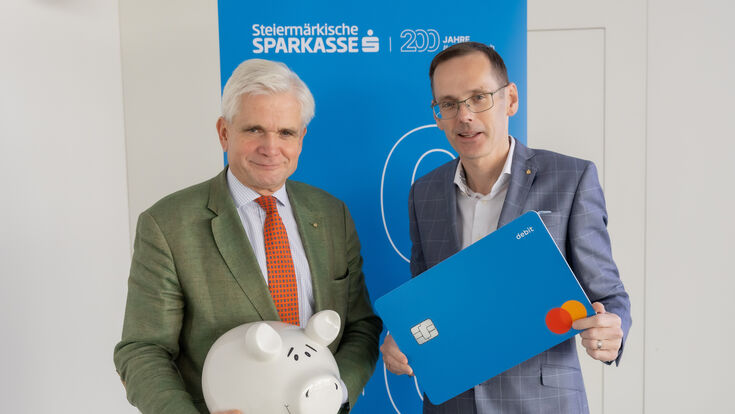 Georg Bucher, Vorstandsvorsitzender, und Oliver Kröpfl, Vorstandsmitglied der Steiermärkischen Sparkasse mit überdimensioniertem Sparschwein und Debitkarte