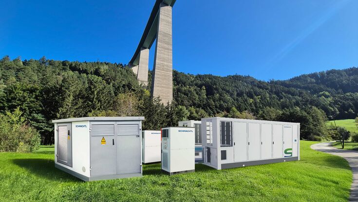 Transformator mit zwei 20-Fuß-Batteriecontainern und zwei Wechselrichtern in grüner Umgebung in Tirol