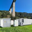 Transformator mit zwei 20-Fuß-Batteriecontainern und zwei Wechselrichtern in grüner Umgebung in Tirol
