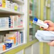 Nahaufnahme auf Hände einer Apothekerin, die Medikamten in ein Regal einschlichtet.