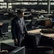 KI-generiertes Bild eines traurigen Manns im Anzug in einer dämmrigen zerstörten Bürohalle