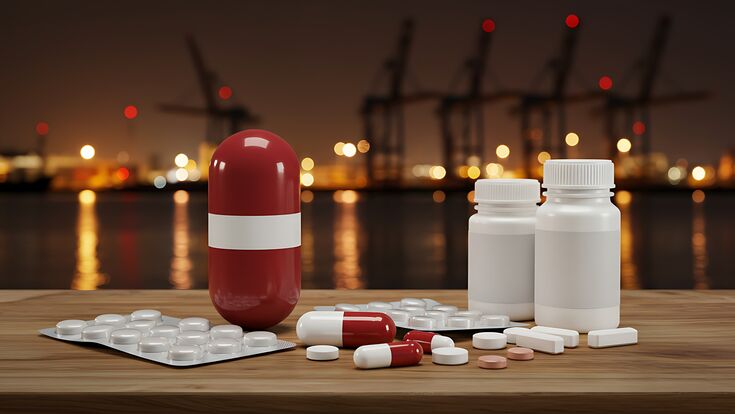Tabletten und Kapseln in rot-weiß-roten Dosen mit Fluss und Industrie in abendlichem Hintergrund