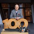 Dr. Nikolas Stihl, Vorsitzender STIHL Beirat und Aufsichtsrat, lehnt auf einer aus Holz geschnitzten "100" mit einer Stihl-Motorsäge davor