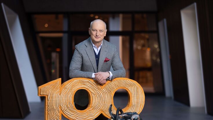 Dr. Nikolas Stihl, Vorsitzender STIHL Beirat und Aufsichtsrat, lehnt auf einer aus Holz geschnitzten "100" mit einer Stihl-Motorsäge davor