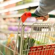 detailansicht auf hände, die einen einkaufswagen mit lebensmitteln durch einen supermarkt schieben