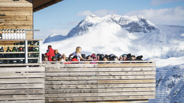 Voll besetzter Balkon eines Lokals auf der Balmalpe Lech in den Vorarlberger Bergen im Winter