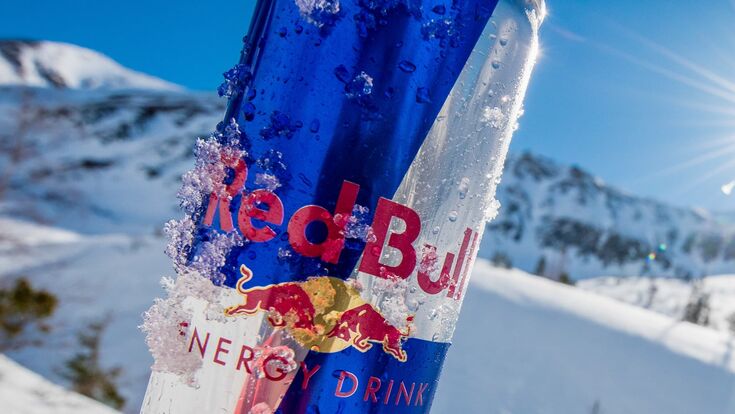 red bull dose leicht mit schnee bedeckt mit winterlandschaft im hintergrund