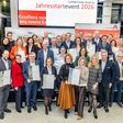 Die ZertifikatsempfängerInnen beim Leitbetriebe Austria Jahresstartevent 2026 halten ihre Zertifikate in die Kamera.