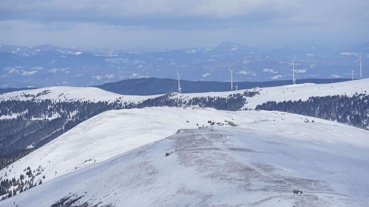 das lavanttal im winter mit windrädern in der ferne