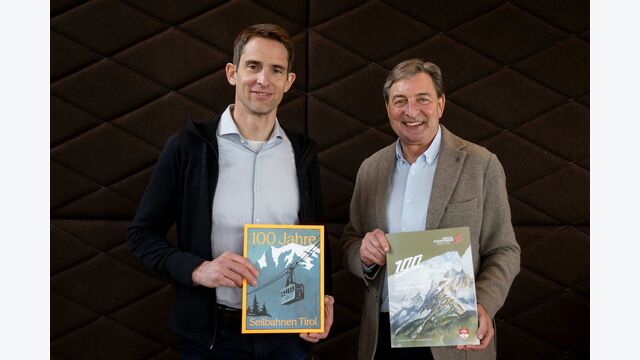 Reinhard Klier, Fachgruppenobmann der Seilbahnen, und Franz Dengg, Geschäftsführer der Tiroler Zugspitzbahn, halten Magazine in die Kamera