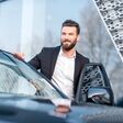 junger mann in business outfit steigt glücklich in einen pkw