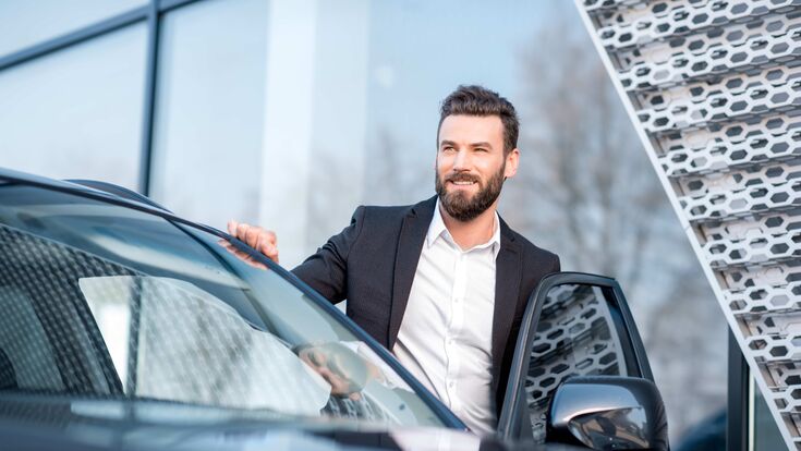 junger mann in business outfit steigt glücklich in einen pkw