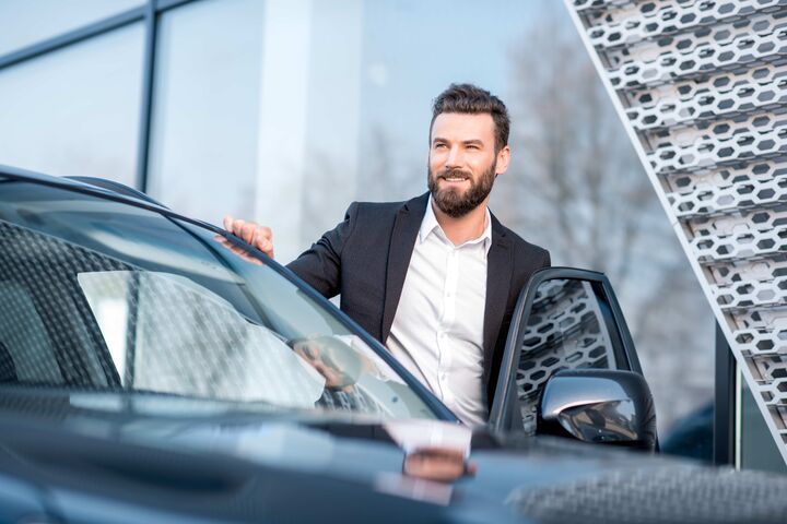 junger mann in business outfit steigt glücklich in einen pkw