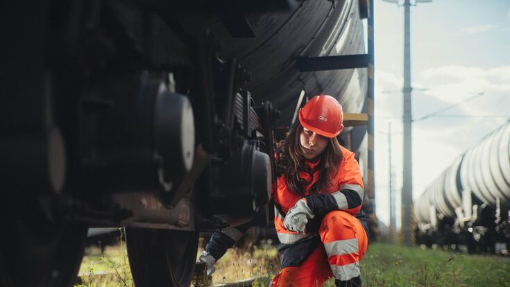 junge öbb mitarbeiterin in schutzhelm arbeitet kniend an einem wagon (verschub)