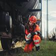 junge öbb mitarbeiterin in schutzhelm arbeitet kniend an einem wagon (verschub)