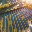 Luftansicht auf mehrere große solarpanele im grünen neben kleiner ortschaft