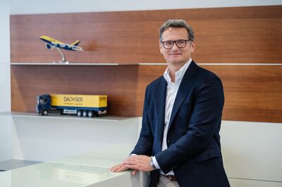Michael Rauhofer, Managing Director European Logistics and Air & Sea Logistics bei Dachser Austria, steht neben modellfahrzeugen von dachser