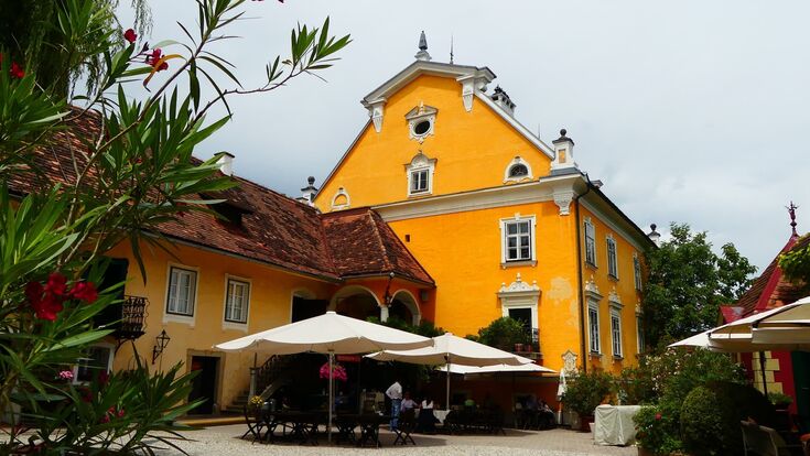 heurigentische und sonnenschirme vor schloss gamlitz in der steiermark