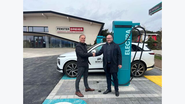 Reinhard Dreier von Fenster Dreier und Sébastien Aldegué von Electra schütteln Hände bei Schnellladestation in Völkermarkt