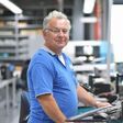 alter mann arbeitet stehend an einem computer in einer industrieanlage