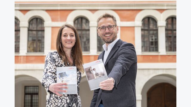 Andreas Kern, Obmann der Fachgruppe Immobilien- und Vermögenstreuhänder in der WKO Steiermark, und Obmann-Stellvertreterin Katharina Waidacher halten den WKO Immopreisspiegel 2026 in die Kamera