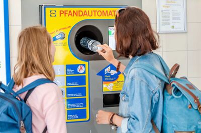 2 junge frauen geben an einem pfandautomat von lidl plastikflaschen zurück