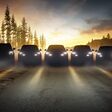 lineup von 5 dunklen ford-autos in waldlichtung mit eingeschalteten scheinwerfern