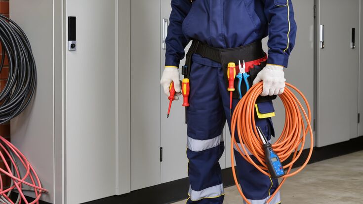 körperausschnitt elektroinstallateur in schutzanzug mit kabel und schraubenzieher