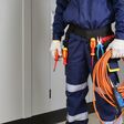 körperausschnitt elektroinstallateur in schutzanzug mit kabel und schraubenzieher