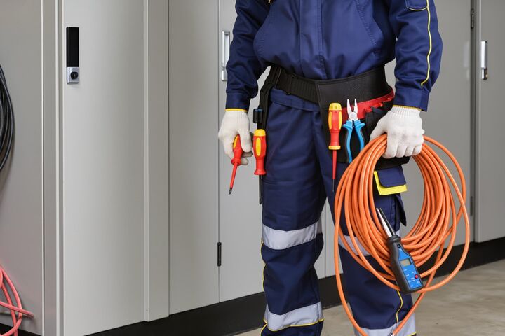 körperausschnitt elektroinstallateur in schutzanzug mit kabel und schraubenzieher