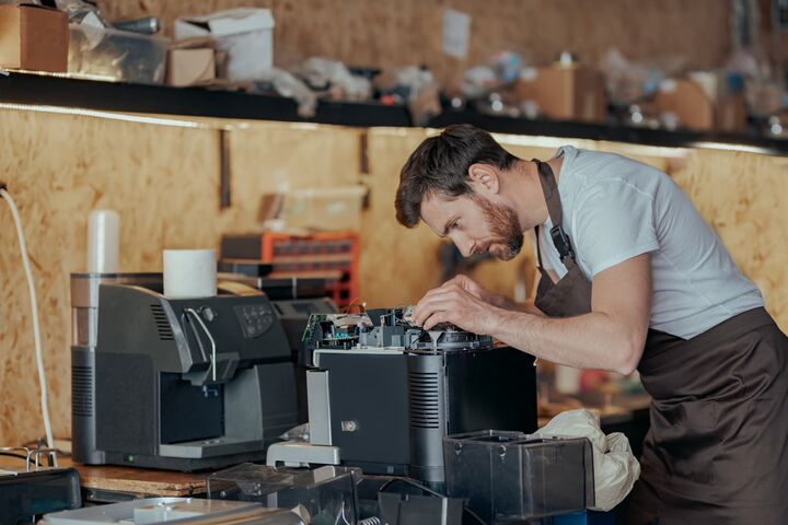 mann repariert in unaufgeräumtem umfeld eine kaffeemaschine