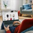 eine frau sitzt auf dem sofa und sieht sich auf dem laptop damenmode auf einem onlinehandel-portal an