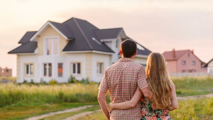 rückenansicht auf pärchen, die auf ein freistehendes haus am land blicken