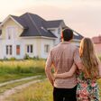 rückenansicht auf pärchen, die auf ein freistehendes haus am land blicken
