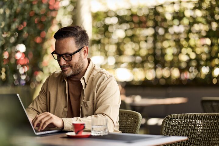 mann arbeitet an laptop an einem kaffeehaustisch