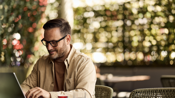mann arbeitet an laptop an einem kaffeehaustisch