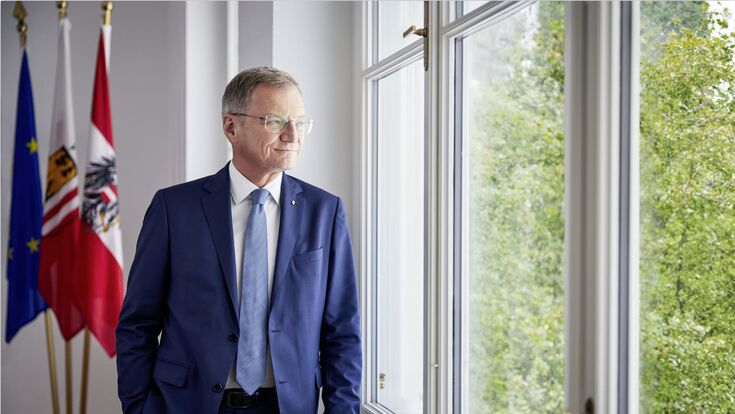 oberösterreichs landeshauptmann thomas stelzer blickt zufrieden aus einem fenster ins grüne