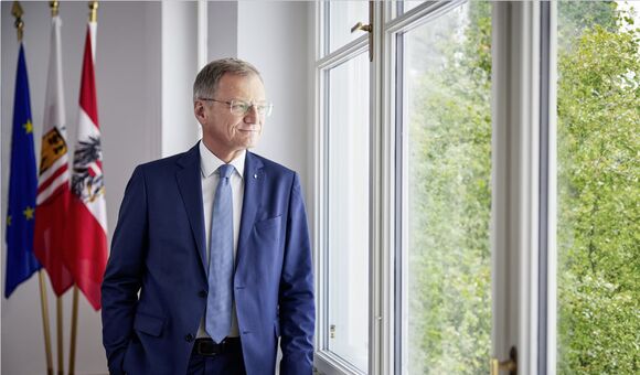 oberösterreichs landeshauptmann thomas stelzer blickt zufrieden aus einem fenster ins grüne